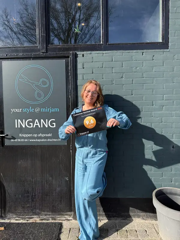 Mirjam lachend bij de ingang van haar salon
